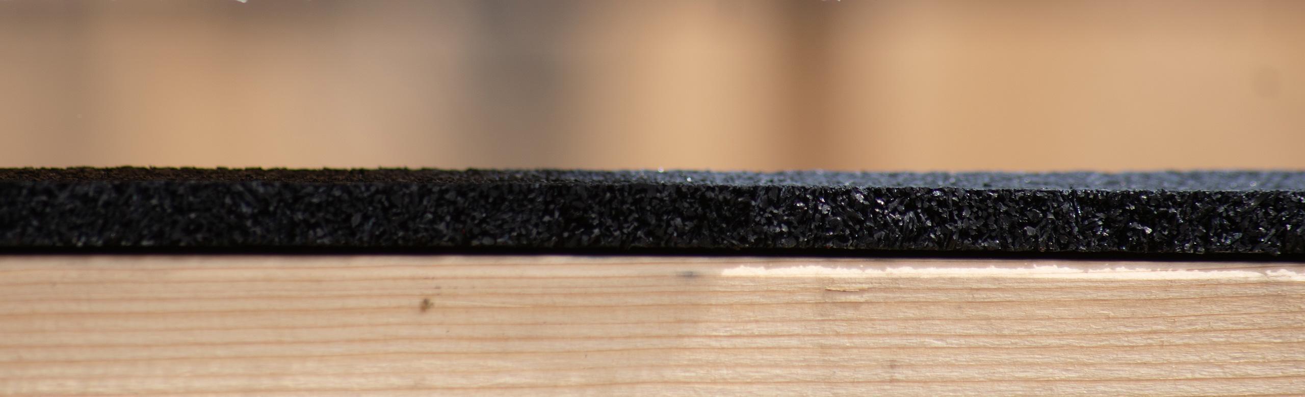 Side view of REGUPOL rubber as it sits on wood. The angle allows for a view of the texture and thickness of the product.
